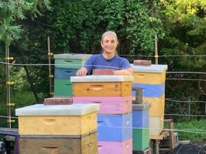 Cathy Blumig standing amid colorfully-painted beehives