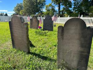 18th and early 19th century tombstones, some with nearby American flags