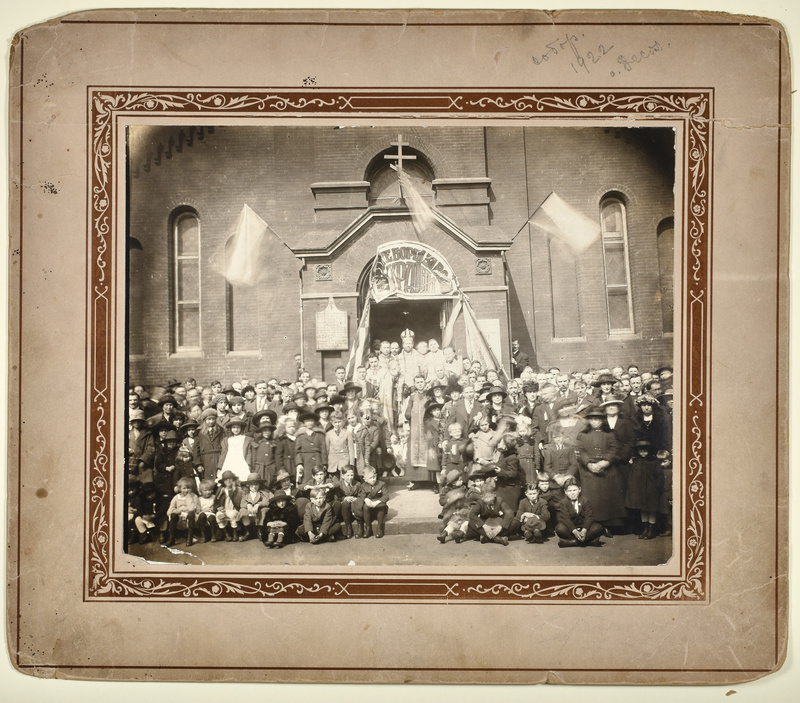Photograph of attendees and visitors in front of Holy Ascension Ukrainian Orthodox Church in Newark. In the center of the back row is [Metropolitan Germanos  (Shehadi) of Zahle and Baalbek](https://orthodoxwiki.org/Germanos_(Shehadi)_of_Zahle), who was the spiritual head of the Ukrainian Orthodox parishes in North America at the time. The banner reads "[illegible]АЙТЕ БОРЦІ ЗА ВОЛЮ УКРАЇНИ" ("[illegible] fighters for the freedom of Ukraine").